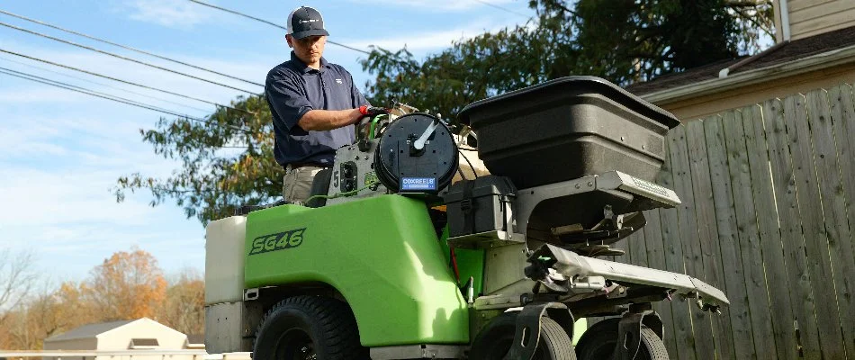 A granular fertilizer spreader fertilizing a sunny lawn.