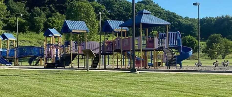 Bright playground with colorful structures in a beautiful park, surrounded by lush green grass in Doylestown, PA.